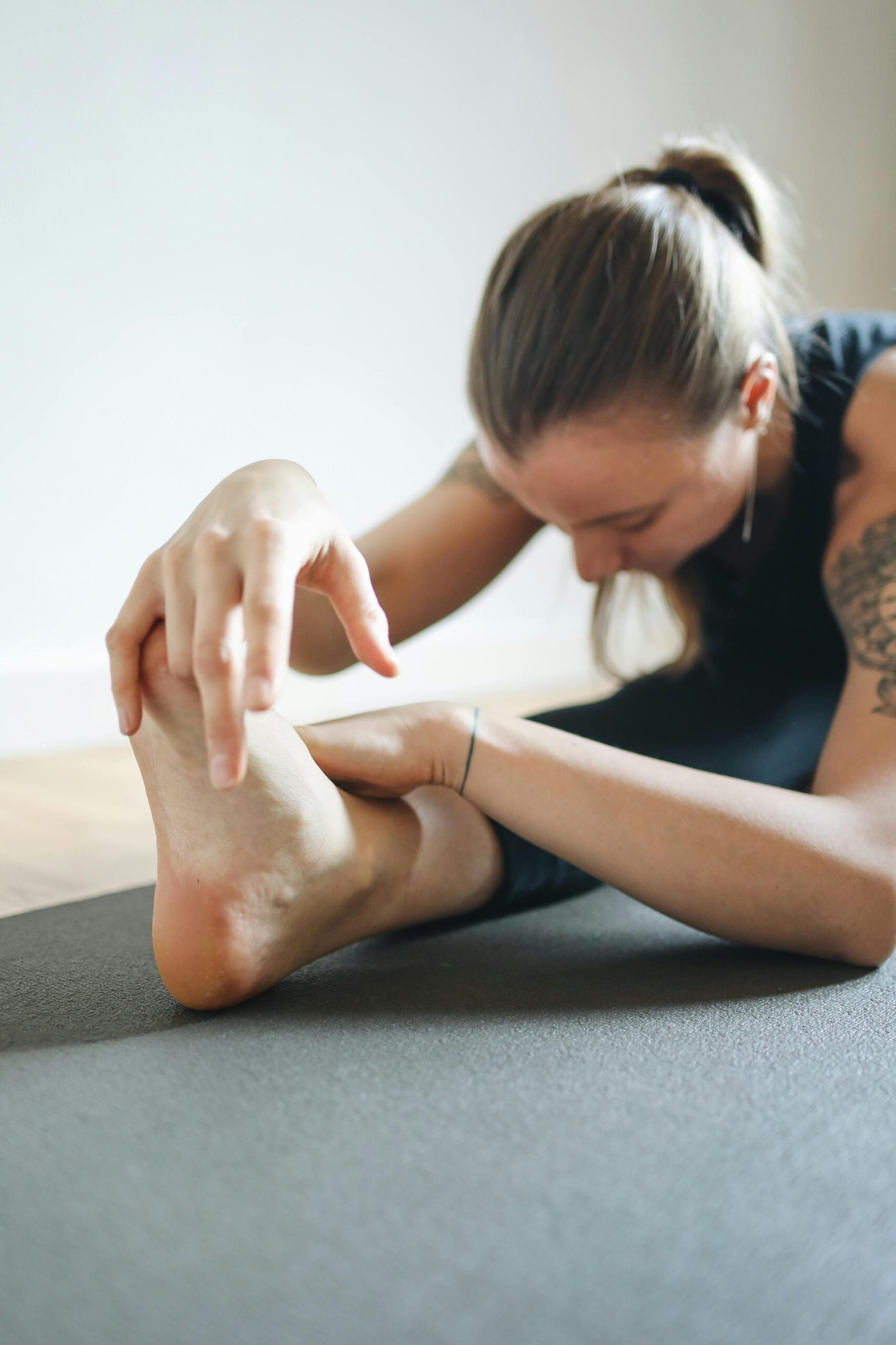 A woman practicing yoga indoors, demonstrating flexibility and focus in a stretching pose.
