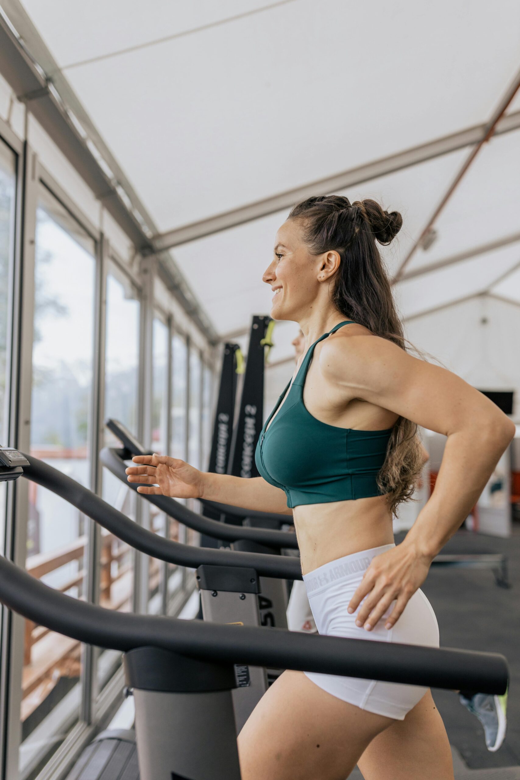 Fit woman jogging on treadmill in an airy gym, focused on health and fitness.
